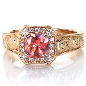 This stunning custom design features a rare colored sapphire center. The rich, fiery colors of the sapphire are accentuated by the warm tones of the yellow gold band. A uniquely shaped halo is bead-set with vibrant diamonds. The wide ring is detailed with gorgeous hand engraved designs and hand formed filigree curls. 