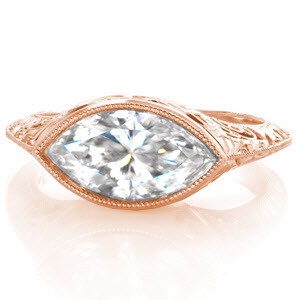 This spectacular custom design is Art Deco inspired. The 1.75 carat marquis cut center diamond is bezel set horizontally and flows beautifully into the knife edge of the band. The side of the ring features a hand engraved band, pockets of hand formed filigree curls, and relief engraving set with round diamonds. 