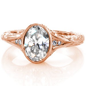 A beautifully intricate ring, Design 3031 features a bezel set 1.20 carat oval cut diamond on a modified knife edge band. Three stones frame the center on either side with milgrain edges leading into the band. The profile is completed with scroll hand engraving, basket filigree and surprise diamonds.
