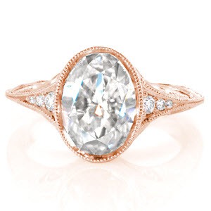 This refined, antique inspired engagement ring features a 2.00 carat oval cut central diamond atop an ornately detailed knife edge band.  The ring's profile reveals hand-formed filigree, surprise diamonds and hand engraving.  The shank's lyrical, wave-like engraving makes for an elegant detail.