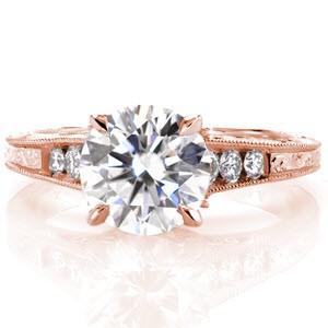 This intricate ring design displays a 1.50 carat round cut diamond set into four prongs. Three round cut diamonds brilliantly frame the center along the top of the ring. A unique marquise diamond petal under the center stone, filigree curls and hand engraving add a truly vintage flair.