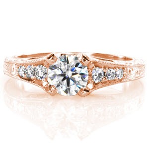 The beautiful shape of the .50 carat round center diamond is splendidly accented by the tapered band of the ring. Three bead set side stones recede down the band and is continued with intricate scroll engraving. Filigree curls and a half wheat engraved pattern on the sides adds a final delicate touch.