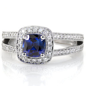 Cielito Sapphire displays a royal blue 1.00 carat cushion cut sapphire in a four prong halo setting. Round diamonds outline the sapphire to embellish the beautiful blue of the center stone. The split shank is lined with bead-set diamonds and accented with milgrain texture for a regal finish. 