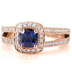 Cielito Sapphire displays a royal blue 1.00 carat cushion cut sapphire in a four prong halo setting. Round diamonds outline the sapphire to embellish the beautiful blue of the center stone. The split shank is lined with bead-set diamonds and accented with milgrain texture for a regal finish. 