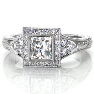Design 3054 offers a lovely 0.70 carat princess cut diamond surrounded by a halo of micro pavé diamonds. The band tappers from a lovely three stone array of diamonds to intricate scroll hand engraving. The side profile of the ring displays hand-formed platinum filigree and matching scroll engraving. 