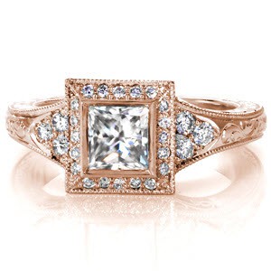 Design 3054 offers a lovely 0.70 carat princess cut diamond surrounded by a halo of micro pavé diamonds. The band tappers from a lovely three stone array of diamonds to intricate scroll hand engraving. The side profile of the ring displays hand-formed platinum filigree and matching scroll engraving. 