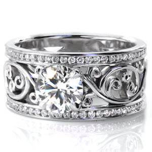 Bold,  high polished filigree scroll work creates a open background for a beautiful 1.00 carat round cut diamond set in a four prong setting. Two rows of channel set diamonds are accented by a high polished finish creating a crisp border for the hand crafted filigree.