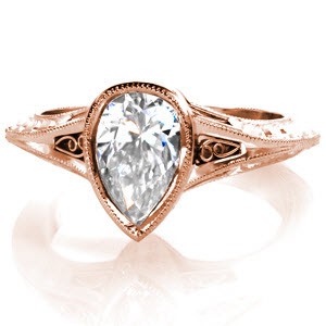 Design 3060 is a charming ring featuring a bezel set 0.80 carat pear-cut diamond on a knife edge band. The central diamond is framed by filigree curls on either side leading into a tapering , double milgrain edge band. The profile of the band includes hand engraved, hard-formed filigree and surprise diamonds.