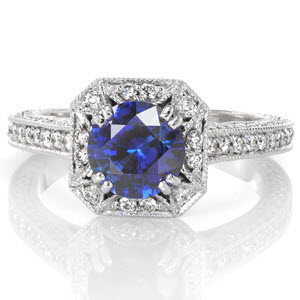 Design 3095 features a unique square halo with clipped corners. The exquisite detail of half-moons accented with micro pavé diamonds surround the 1.30 carat round blue sapphire. Bead-set stones continue down the band and form a diamond patterned profile view.