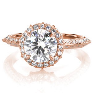 This shining round brilliant halo design is uplifted by a marquise shaped pierced design to enhance the magnificence of this extraordinary design.  Micro pavé exquisitely line each side of the band evoking a glamorous appeal. The edges are refined with hand applied milgrain for an elegant touch. 