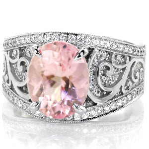 A 2.70 carat rosy hued oval morganite is complimented by glimmering 14K white gold surroundings in this custom design. Contrast is seen again in the high polished spirals curling against a recessed hand stippled background. The flared band is framed by bead set micro pavé diamonds and milgrained edges.