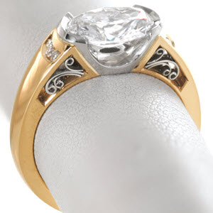 Beautiful two tone oval engagement ring in Indianapolis features a yellow gold band with a platinum half bezel center setting. The band is adorned with channel set diamonds and hand formed, platinum filigree curls. 