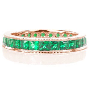 The Birthstone Eternity Band features lush princess cut emeralds that continue around the entire ring for a seamless finish. The emeralds are channel set within a band of high polished 14 karat white gold. The finest quality hand-applied milgrain detail finishes the band outer edges.