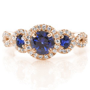 Design 3223 diaplays sapphires of striking blue within a unique woven band.  Crafted in 14 karat white gold, the  micro pavé band flows with a woven form around the three round cut sapphires creating a halo. Each sapphire is set in the halo with a four prong style.