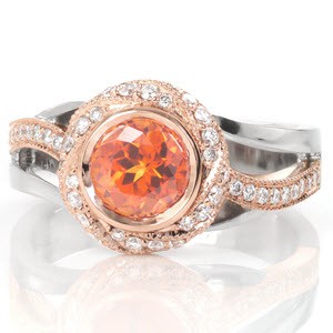 Design 3227 features a fiery orange 1.00 carat sapphire in a woven halo. The warm peachy hues of the rose gold halo and band perfectly compliment the center gem. The split shank of rose and white gold adds movement and dimension that flow with the halo. White diamonds adorn the halo and rose gold portion of the band.