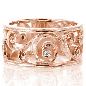 The graceful curves of Design 3235 adds movement to this exquisite signature wide band. The curving 14k white gold swirls is framed in milgrain and embellished with bezel set diamonds. The center pattern is bordered by double milgrain bands to form a beautifully balanced design.