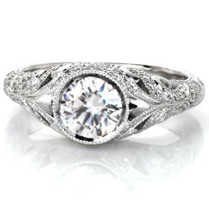 The Fitzgerald evokes images of the elegant 1920's and the decadent gems worn during that time. A bezel set center stone is the focus of a band made from swirling patterns. The upper scrolls are adorned with round brilliant diamonds while the lower sections are masterfully hand engraved with relief style scroll-work. 
