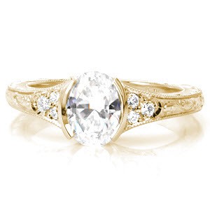 Vintage inspired custom engagement ring in Detroit with an oval cut center diamond held in a half bezel and bordered by beadset diamonds and hand engraving.