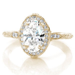 Exquisite yellow gold halo engagement ring in Knoxville features an oval center diamond. The intricate band features hand carved relief engraving, milgrain, and diamonds. 