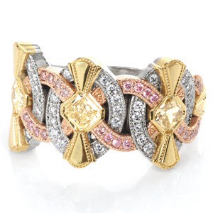 An intricate Art Deco inspired band, Tiara is a stunning collection of gold hues. Diamonds presented are radiant cut yellows with full bezel, surrounded by yellow gold fans. Round cut bead set pink diamonds in rose gold arches, and round cut diamonds within the oval shapes. The split shank band tapers for comfort.