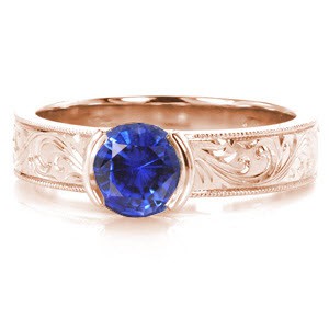 Rose gold custom engagement ring in Toronto with scroll hand engraving and a round blue sapphire center stone.