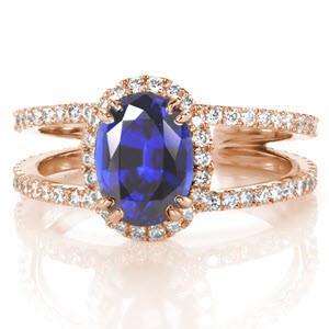 A grand 1.50 carat oval cut blue sapphire creates a beautiful statement of sophistication for our Maverick design. Crafted in 14k white gold, hand formed U-Cut prongs accentuate diamonds around the halo and band. A split shank flares towards the center stone and also tapers at the band bottom for a comfortable fit.