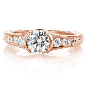Design 3312 has vintage elements incorporated within a style for today. Crafted in 14k white gold, the setting has two styles of hand engraving and adorned with hand formed filigree curls. The flared band gives prominence to the half bezel set 0.70 carat center diamond and trio of round diamonds graduating in size.