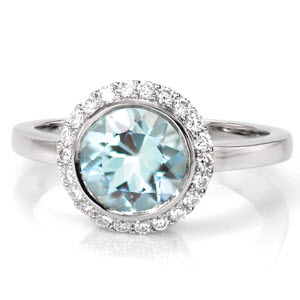 Crafted in Platinum, Design 3318 evokes a serene quality with a 1.50 carat round cut Aquamarine center gemstone. A petite halo of round cut diamonds within shared prongs soften the center stone full bezel. A high polish band reveals six baskets of hand formed filigree work.