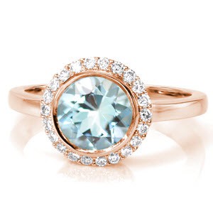 Crafted in Platinum, Design 3318 evokes a serene quality with a 1.50 carat round cut Aquamarine center gemstone. A petite halo of round cut diamonds within shared prongs soften the center stone full bezel. A high polish band reveals six baskets of hand formed filigree work.