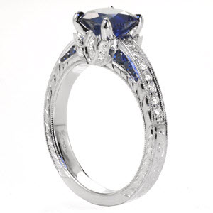 Regal blue sapphires add to the vintage appeal of this custom engagement ring in Chicago. The band is accented with hand engraving, filigree, and a diamonds.