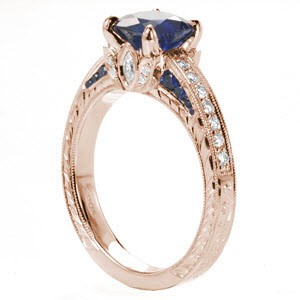 St Petersburg custom engagement ring with a cushion cut blue sapphire center stone atop a hand engraving and floral designed band.