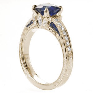 Stamford custom engagement ring with a cushion cut blue sapphire center stone atop a hand engraving and floral designed band.