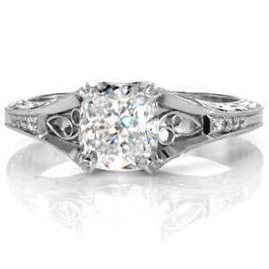 A 1.20 carat cushion cut center stone is fashioned in this vintage inspired design. Hand wrought filigree adds a decorative statement to the top and sides of the ring. The scroll pattern is highlighted by the contrast of the carefully stippled background. Accent diamonds adorn the band to add sparkle and brilliance.