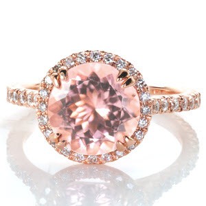 Design 3345 is set with an ethereal 2.20 carat round cut morganite center gemstone and crafted in 14k rose gold. Intricate V-Cut prongs are individually formed by hand, and set with round cut diamonds around the halo and sides of the band. The halo is raised slightly to accommodate a matching wedding band.