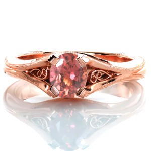 The warmth of a rose gold setting was the ideal compliment to the extraordinary mosaic-like 0.90 carat oval orange sapphire featured in Design 3365. Hand formed filigree curls adorn either side of the central sapphire. This modified vintage inspired setting is detailed with milgrain edging. 