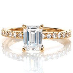 Design 3369 couples a classic four prong center stone setting to an elegant hand carved u-cut diamond band creating a refined look with a timeless appeal. A 1.20 carat emerald cut diamond takes the spotlight in this luscious yellow gold custom engagement ring.