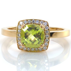 A cushion cut gemstone adds a modern angular outline to a classic halo setting. Design 3370 features a 1.50 carat olive green peridot held in double prongs and framed by twinkling bead set diamonds. A hint of milgrain edging adds texture to this very colorful custom design.