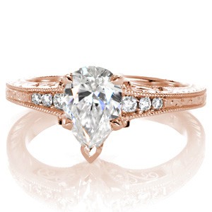 Rose gold custom engagement ring in Phoenix with a unique pear cut center diamond held on a band featuring bead set diamonds and hand engraving.