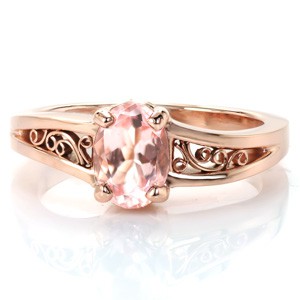 Stunning rose gold and sapphire engagement ring in Tulsa. This gorgeous design features a pale, peachy-pink oval center gem (can me morganite or sapphire)  that is perfectly complimented by the warm hues of the rose gold. The design is completed with hand wrought filigree curls. 