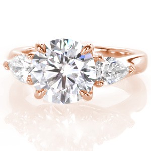 An arching trellis design offers the perfect setting for the stunning 1.70 carat round brilliant diamond featured in Design 3391. The round side diamonds often seen in a three stone ring are replace with visually interesting pear shapes. The pronged horizontal set pear side stones create a streamlined look.
