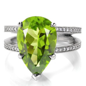 Design 3397 is a contemporary style engagement ring with a bold presence. Crafted in 950 Platinum Ruthenium, the center stone is a vibrant 6.00 carat pear cut natural Peridot gemstone. The split shank is finished with perfectly matched round cut bead set diamonds with milgrain edges.