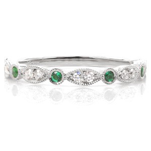 Design 3398 is a colorful take on our popular scalloped wedding band design. This version of the ring features vibrant bezel set round emeralds stationed between bead set diamond marquise shapes. The band is finished with milgrain edging and the profile view features delicate scroll hand engraving.
