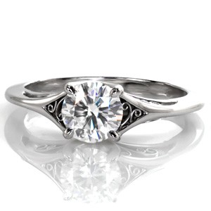 Delicate hand-formed platinum filigree is the perfect addition to this classic solitaire engagement ring. The graceful split of the band creates open pockets for filigree and frames the stunning 0.70 carat round diamond. The side view is mirrored with a smooth high polish finish and scrolls of filigree curls.
