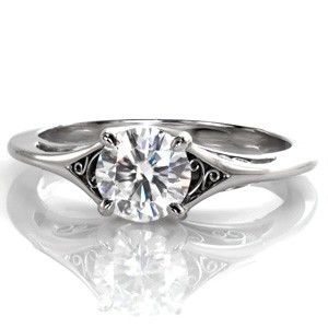 Delicate hand-formed platinum filigree is the perfect addition to this classic solitaire engagement ring. The graceful split of the band creates open pockets for filigree and frames the stunning 0.70 carat round diamond. The side view is mirrored with a smooth high polish finish and scrolls of filigree curls.
