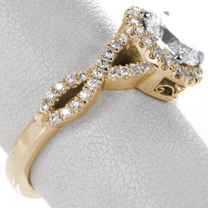 Unique infinity engagement rings in Charleston. This halo engagement ring features a diamond band with a woven infinity symbol twist. The basket under the oval shaped diamond halo features two pockets of hand formed filigree. 