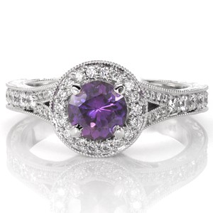 This vintage inspired beauty is adorned with brilliant micro pavé diamonds along the split shank, round halo, and halo apron. The vibrant round purple sapphire is fashioned in a four prong setting in the center of the diamond halo. Milgrain, filigree and scroll engraving enhances its antique charm.   