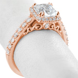 Rose gold engagement rings in Cedar Rapids with gorgeous filigree curls and marquise surprise diamonds. This cushion cut halo ring is shown in rose gold with a micro pave band.