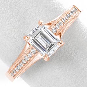 Unique rose gold engagement ring in Fort Worth features a stunning emerald cut center diamond and wide, rose gold and diamond band. The sides are elegantly detailed with intricate filigree curls. 