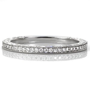 Design 3439 is a step above the traditional diamond wedding band. The top is adorned with brilliant bead-set diamonds and the sides feature unique relief style hand engraving. These intricately hand engraved scroll patterns stand out against the stippled background. Milgrain textured edges create a cohesive final look.