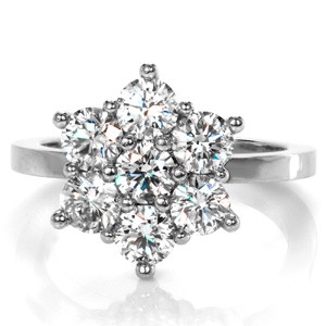 Design 3444 features a magnificent cluster of sparking round brilliant diamonds. This Mid Century inspiration showcases a halo of diamonds that match in size to the center stone. The arrangement of diamonds creates a distinct floral appeal. Milgrain texture is applied to the prongs for a vintage tribute.   